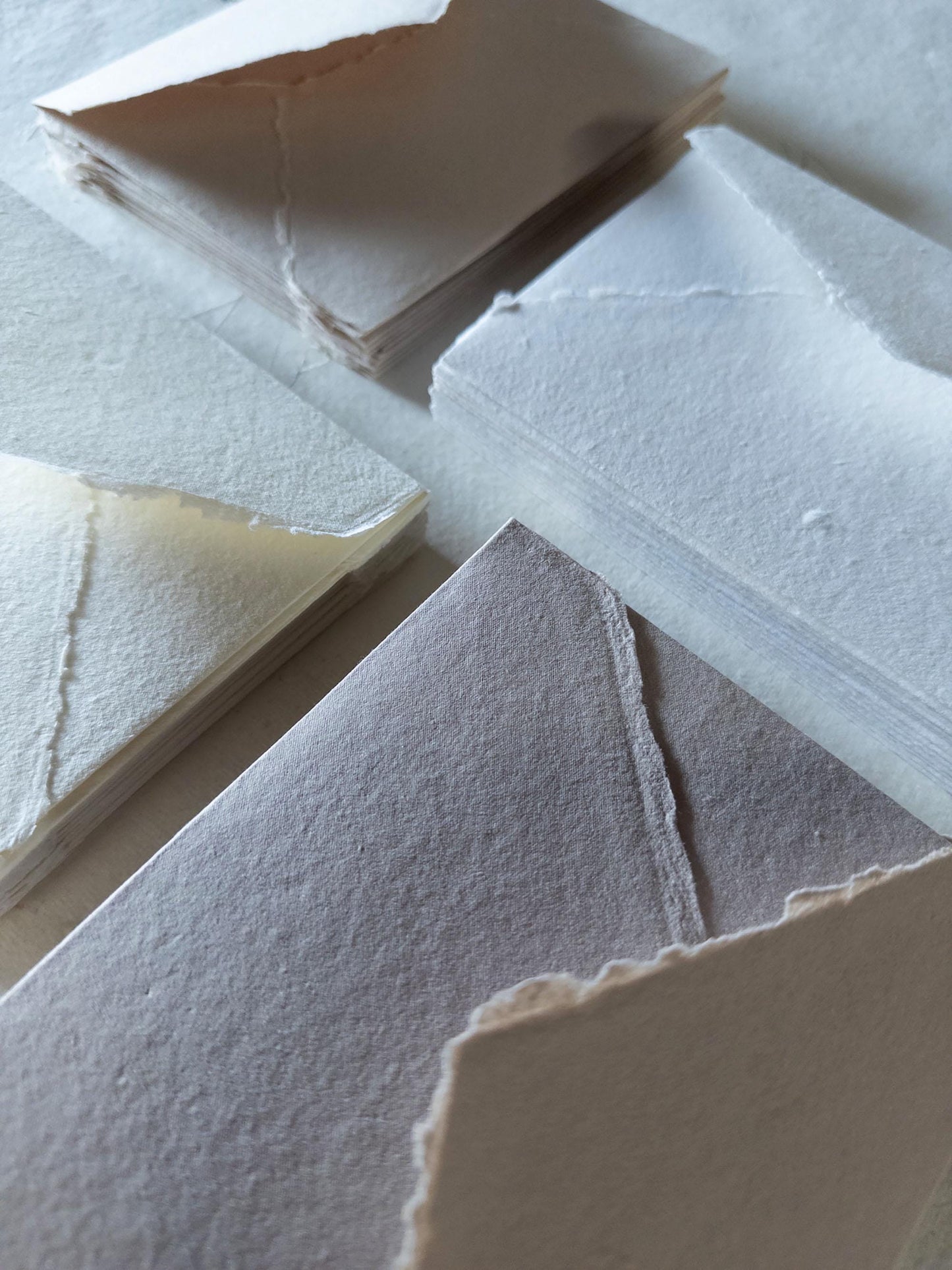 Set of handmade envelopes in assorted natural colors: white, ivory, beige, and earth tones - crafted from high-quality cotton rag paper with a deckle edge.