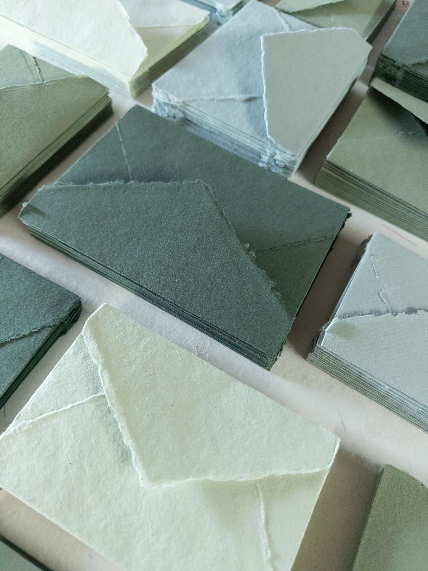 Close-up of a textured olive green envelope with deckle edges, showcasing the intricate craftsmanship of handmade cotton rag paper.